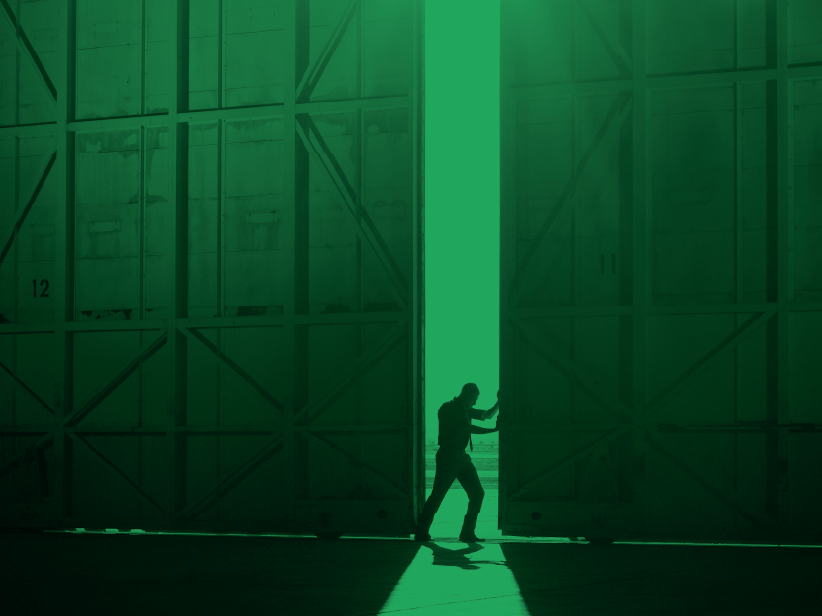 Person walking into light through large doors.